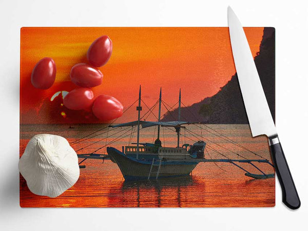 Boat sailing in the orange sunset Glass Chopping Board